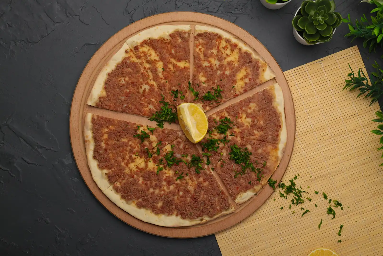 Siyah taşta kesilmiş lahmacun, limon dilimi ve maydanoz