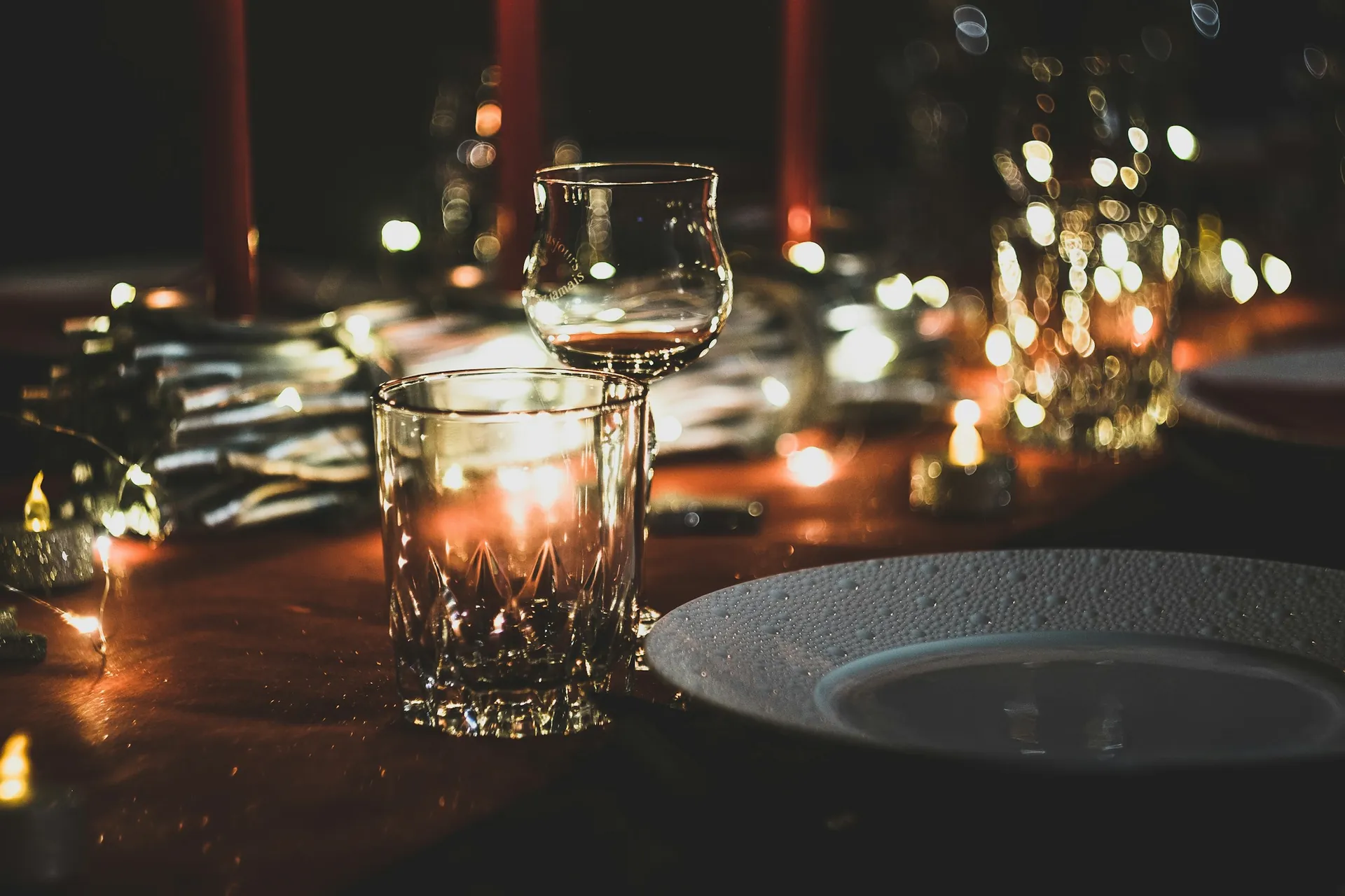 Mum ışığında masa üstünde kristal bardak ve tabak