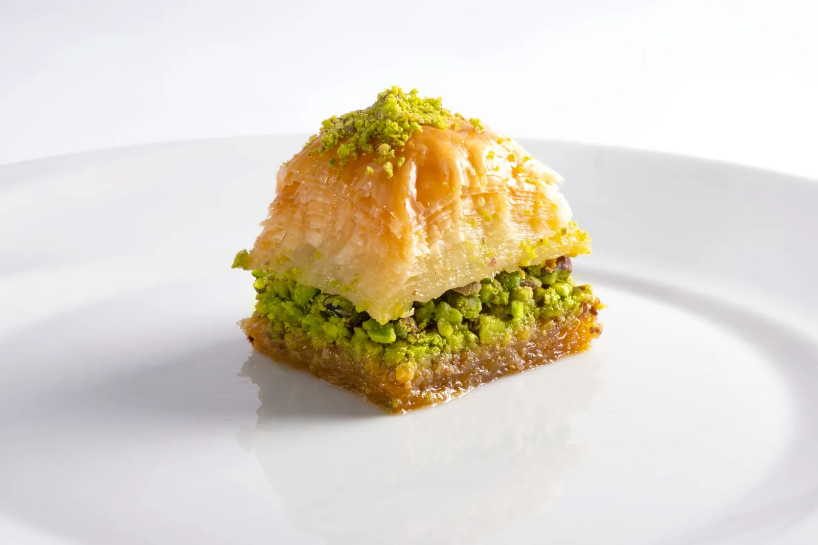 Beyaz tabakta fıstıklı baklava dilimi